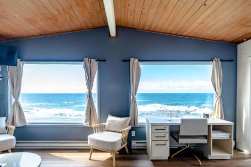 um quarto com paredes azuis e janelas com uma secretária e cadeiras em Seagull Beachfront Inn em Lincoln City