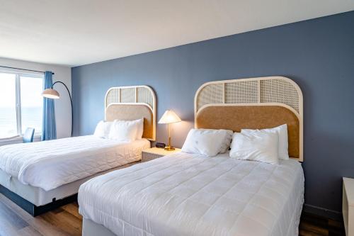 two beds in a room with blue walls at Seagull Beachfront Inn in Lincoln City