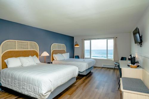 a hotel room with two beds and a large window at Seagull Beachfront Inn in Lincoln City