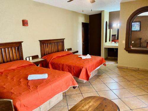 a hotel room with two beds with orange sheets at Hotel Cabañas Santa Cruz in Oaxtepec