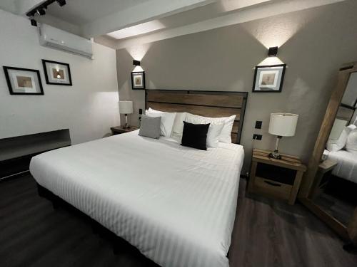 um quarto com uma cama grande com lençóis brancos e almofadas em SOLSTICIO 212 em Cholula