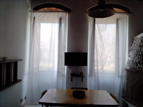 ein Wohnzimmer mit einem Tisch und 2 Fenstern in der Unterkunft Casina del porto in Livorno