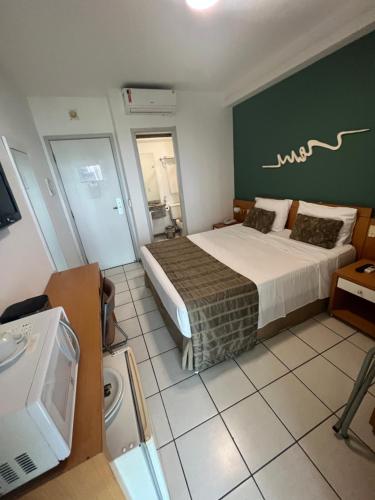 Un dormitorio con una cama grande y una pared verde en Praia do Canto Apart Hotel Frente Mar, en Vitória