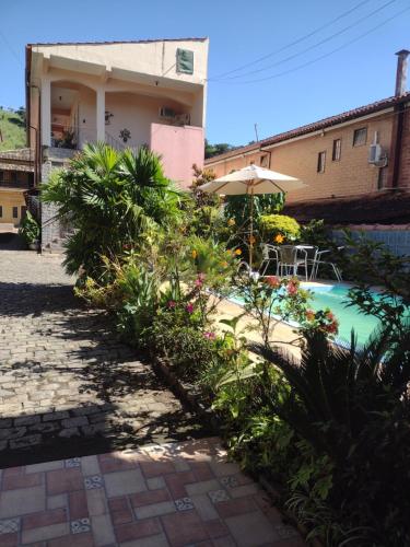 a house with a swimming pool and an umbrella at Pousada Oca Porã in Conservatória