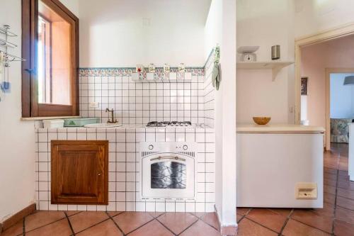 kuchnia z kuchenką i białą ścianą wyłożoną kafelkami w obiekcie {Villa Jacuzzi Privata}sul mare di Fontane Bianche w mieście Fontane Bianche