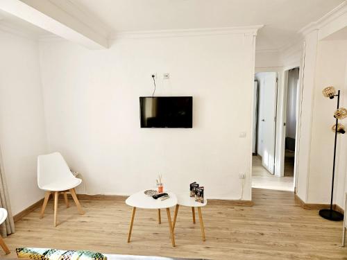 a living room with two tables and a tv on the wall at Apartamento Familiar en Triana in Seville