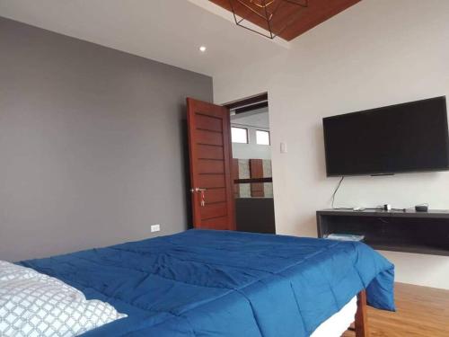 1 dormitorio con 1 cama azul y TV de pantalla plana en Brand new house with 3-bedroom and free parking en Guiguinto