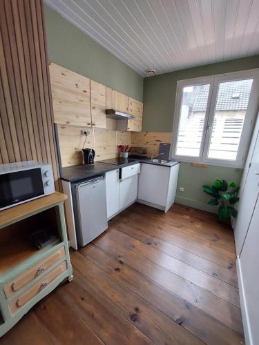 eine Küche mit weißen Geräten und Holzböden in der Unterkunft Natif 4 personnes in Aire-sur-la-Lys