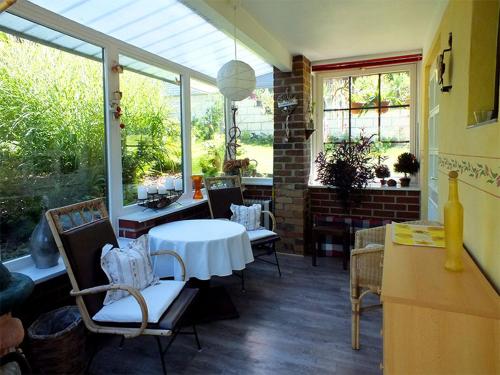 eine Terrasse mit einem weißen Tisch, Stühlen und Fenstern in der Unterkunft Ferienhaus Zum Gründel in Prossen