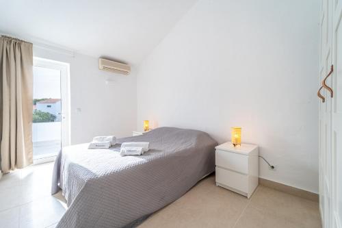 a white bedroom with a bed and a window at Villa Alfamar by HelloVacations in Albufeira