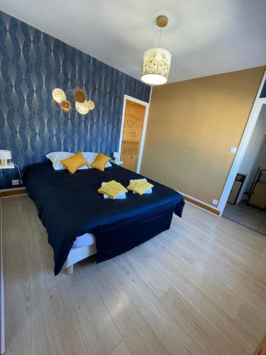Un dormitorio con una gran cama azul con almohadas amarillas en La petite maison Pasteur, en Angers