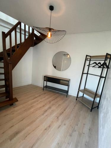 Habitación con escalera, mesa y espejo. en La petite maison Pasteur, en Angers
