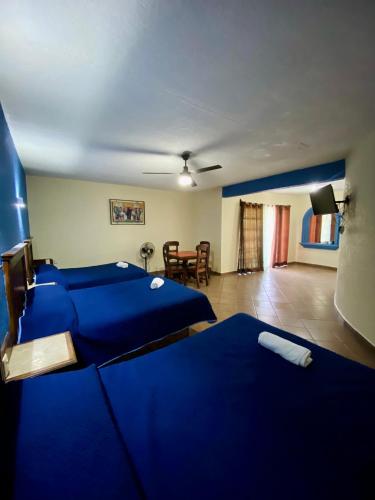 a bedroom with two blue beds and a dining room at Hotel Cabañas Santa Cruz in Oaxtepec