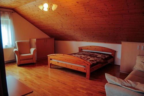 a bedroom with a wooden bed and a chair at ZOLI'BÁ Apartman in Gyöngyösfalu
