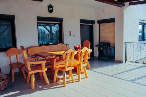 una mesa de madera y sillas en un patio en ZOLI'BÁ Apartman, en Gyöngyösfalu
