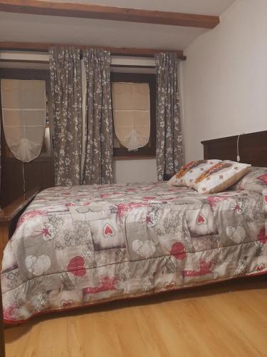 ein Schlafzimmer mit einem Bett mit einer Decke und Vorhängen in der Unterkunft Casa Vacanze da Lino in Nus