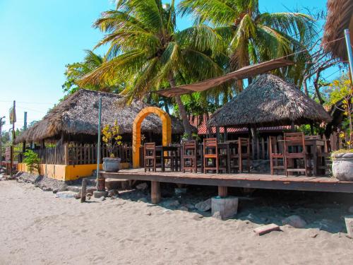 a resort on the beach with chairs and palm trees at Hotel Restaurante Spa La Barca de Oro in Las Peñitas