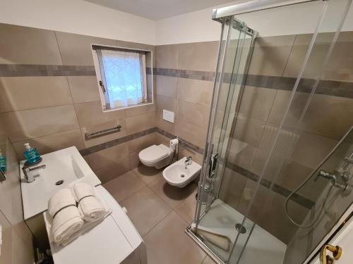 een badkamer met een douche, een wastafel en een toilet bij Casa Sole in Costermano