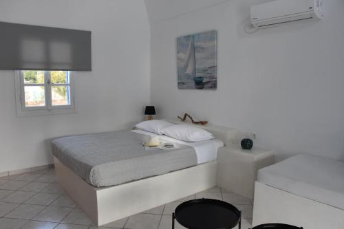 a white bedroom with a bed and a window at Spacious veranda, house for 3, in the village. in Kamari