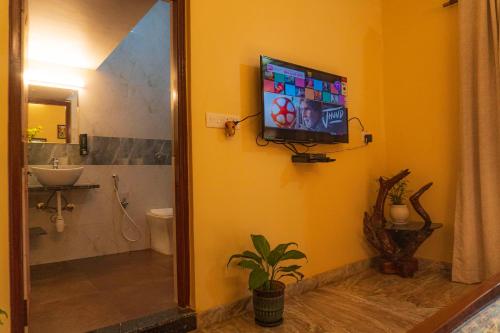 a bathroom with a television on a wall with a toilet at Casa de Alnena in Benaulim