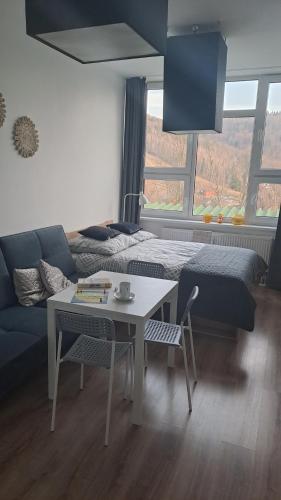 a living room with a couch and a table and a bed at Apartamenty Ustroń Jaszowiec 92 abc in Ustroń