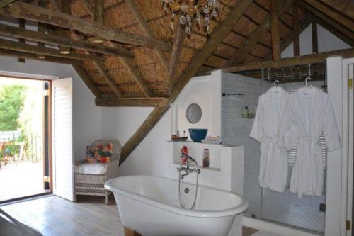 a bathroom with a bath tub in a room at Petite France:luxury thatched 4BRcottage with pool in Franschhoek