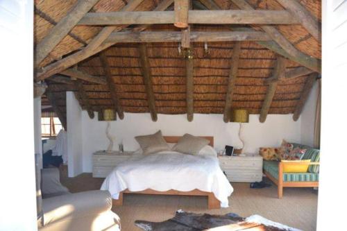 a bedroom with a bed and a wooden ceiling at Petite France:luxury thatched 4BRcottage with pool in Franschhoek
