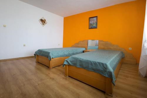 two beds in a room with orange walls and wooden floors at къща Слави in Oreshak