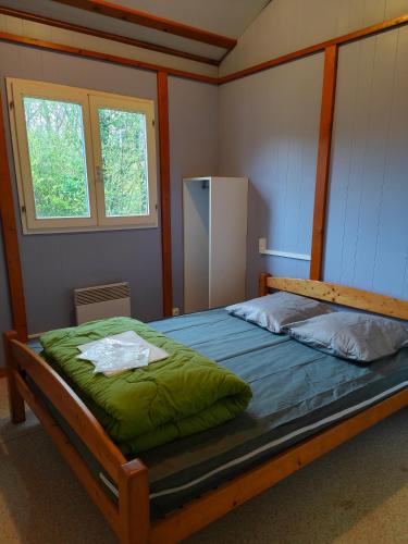 a bedroom with a bed with green sheets and two windows at Camping Onlycamp Les Deux Rives in Lannion