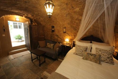 1 dormitorio con 1 cama, 1 silla y 1 ventana en Casa de las Campanans en Iznájar