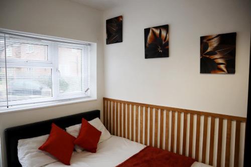 Un dormitorio con una cama con almohadas rojas y una ventana en 259A Queen Ediths Way, en Cherry Hinton