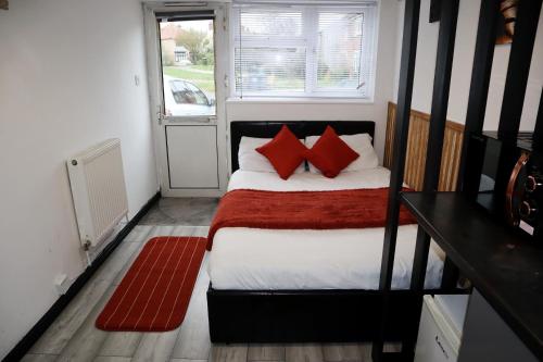 a small bedroom with a bed with red pillows at 259A Queen Ediths Way in Cherry Hinton