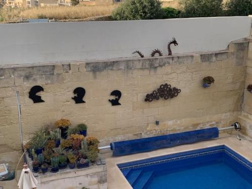 a brick wall with a swimming pool and some plants at Dar Dragun: luxury 3BR bright spacious house & pool in San Lawrenz