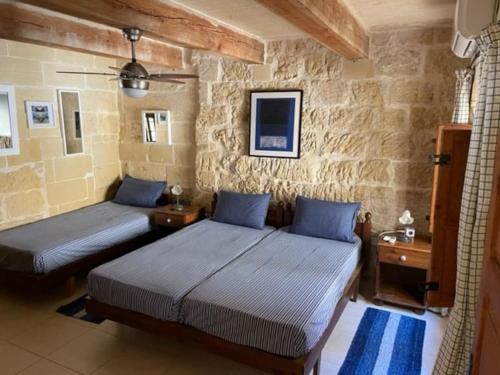 Habitación con 2 camas y paredes de piedra. en Dar Dragun: luxury 3BR bright spacious house & pool, en San Lawrenz