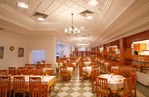 a dining room with tables and chairs and a chandelier at Al Jazira Beach & Spa- All Inclusive - Families and Couples Only in Houmt Souk