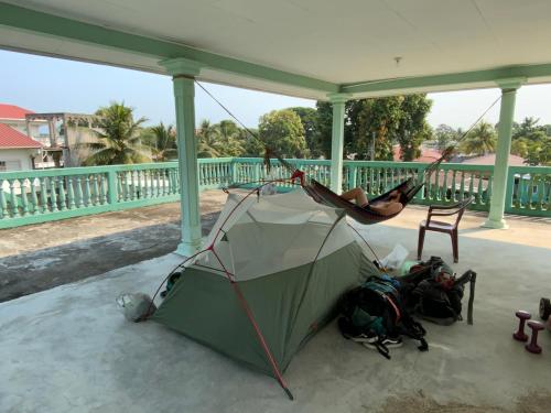 a person laying in a hammock on a porch at Hostel Casa Verde, Tela Atlantida. in Tela