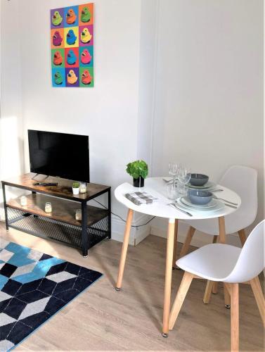 Il comprend un salon doté d'une table blanche et d'une télévision. dans l'établissement Le Colvert-Charmant appart proche centre et gare, au Havre