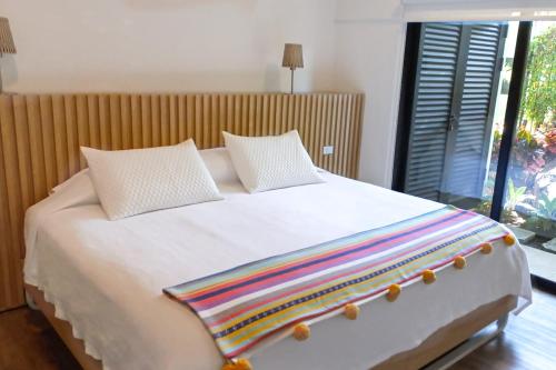 Una cama blanca con dos almohadas y una manta de arco iris. en Colina Inn, en Escazú