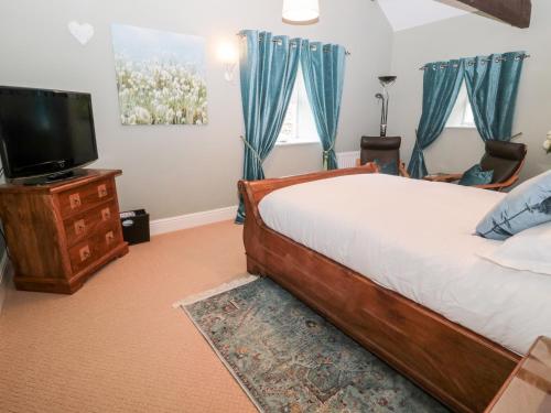 a bedroom with a bed and a flat screen tv at The Steadings in Morpeth