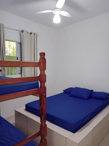 een slaapkamer met een bed met blauwe lakens en een ventilator bij Chalés Jussara in Ubatuba