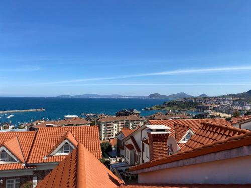 vistas a una ciudad con techos rojos y al océano en Villa OLYMPIA, en Castro Urdiales