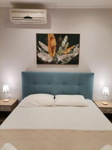 a bed with a blue headboard and a painting on the wall at Sea Salt Apartments in Samos