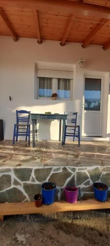 a patio with two chairs and a table with pots at Το σπίτι της Ελένης in Vlakhiá