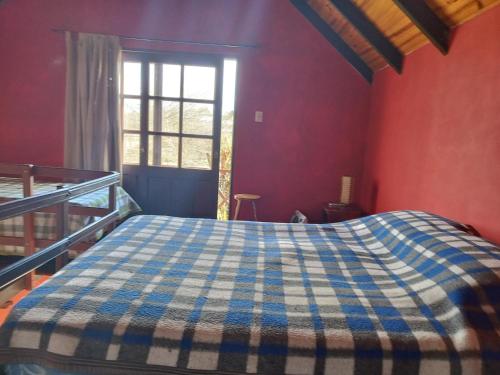 um quarto com uma cama com um cobertor azul e branco. em Mar de Colores em Punta Del Diablo