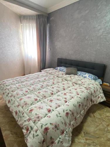 a bed with a floral comforter in a bedroom at Appartement Lux Safi in Safi