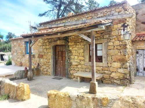 un edificio de piedra con un banco delante en EcoNature Dagaio Handmade Paradise, en Ericeira