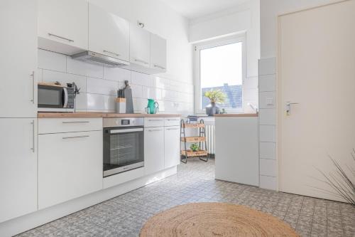 Center Dream Apartment - Netflix في كريفيلد: مطبخ أبيض مع دواليب بيضاء وميكرويف