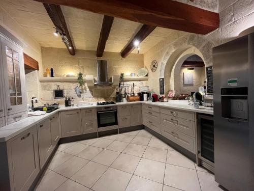 a large kitchen with white cabinets and appliances at Tal-Mans Farmhouse Gozo in Sannat