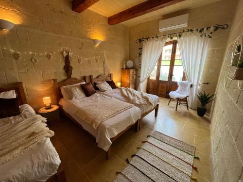 1 dormitorio con 2 camas y ventana grande en Tal-Mans Farmhouse Gozo, en Sannat