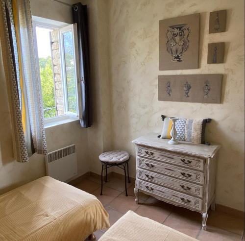 ein Schlafzimmer mit einer Kommode und einem Fenster in der Unterkunft Bastidon à Gordes avec piscine in Gordes